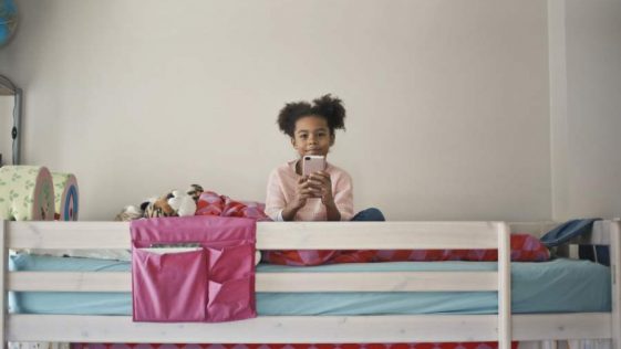 Petite fille assise sur un lit en hauteur