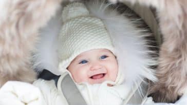 happy laughing baby girl in a warm stroller wearing a winter jac