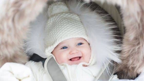 happy laughing baby girl in a warm stroller wearing a winter jac