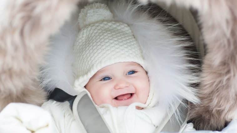 happy laughing baby girl in a warm stroller wearing a winter jac