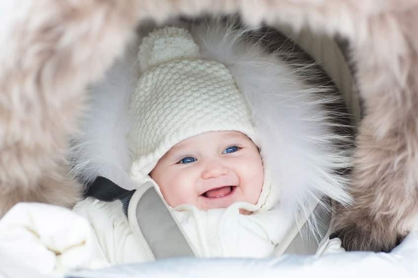 happy laughing baby girl in a warm stroller wearing a winter jac
