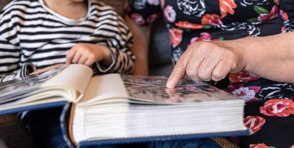 petite fille regardant album photo avec grands parents