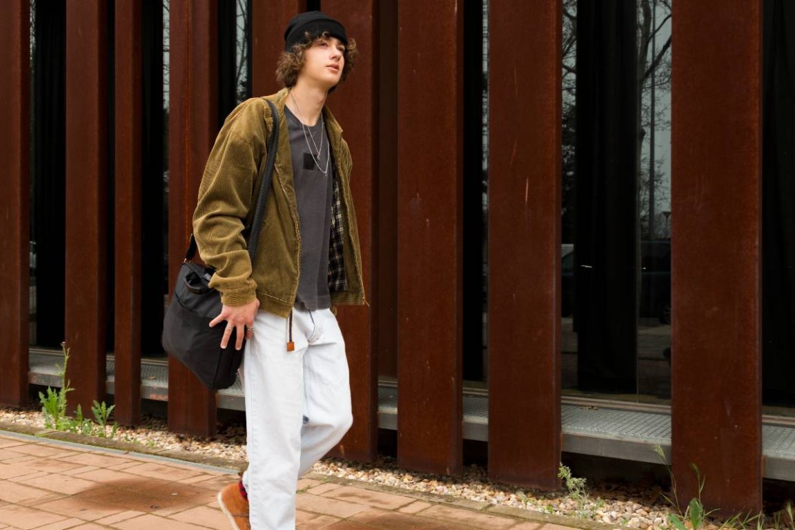 jeune homme marchant devant un mur en acier corten