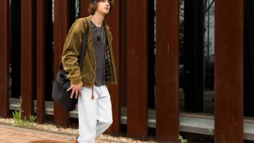 jeune homme marchant devant un mur en acier corten