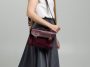 small red leather bag over a woman shoulder on a white background. shoulder handbag. woman in a white shirt and grey skirt and with a red handbag. style, retro, fashion, vintage and elegance.
